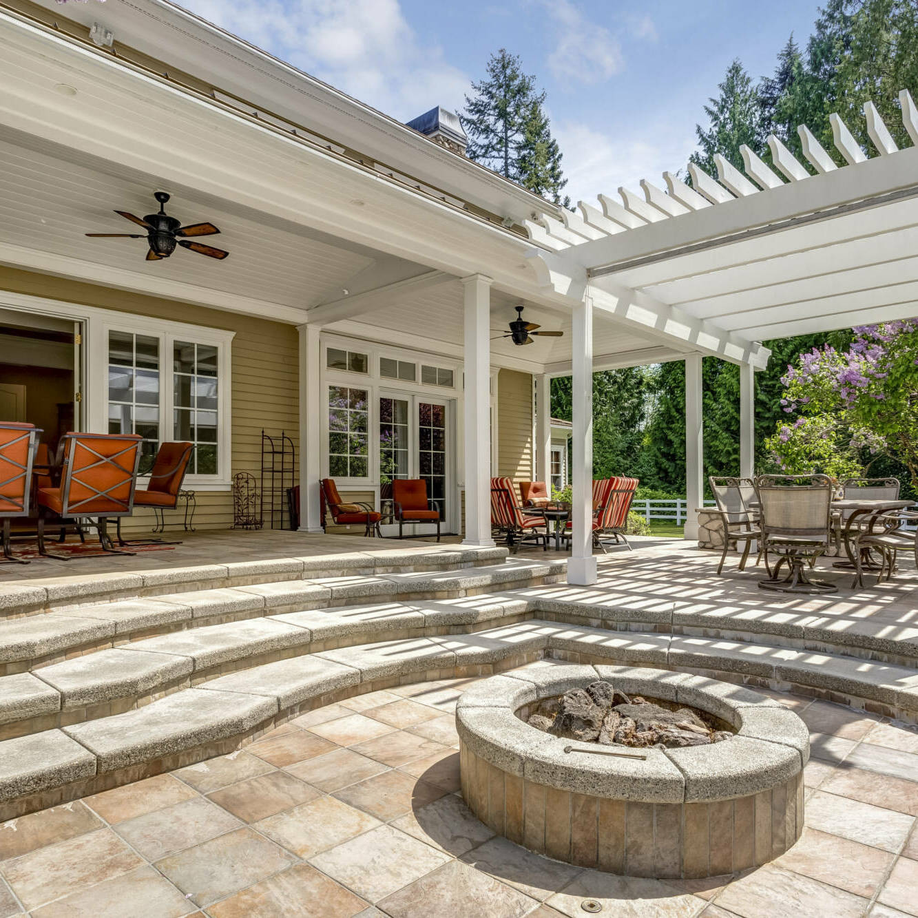 Lovely outdoor deck patio space with white pergola, fire pit in the backyard of a luxury house.